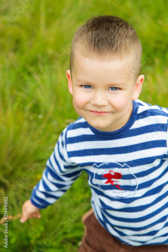 A boy in a striped t-shirt posing on the grass in the garden photo