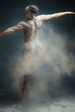 Dancing in flour concept. Muscle fitness guy man male dancer in dust / fog. Guy wearing white shorts making dance element in flour cloud on isolated grey background