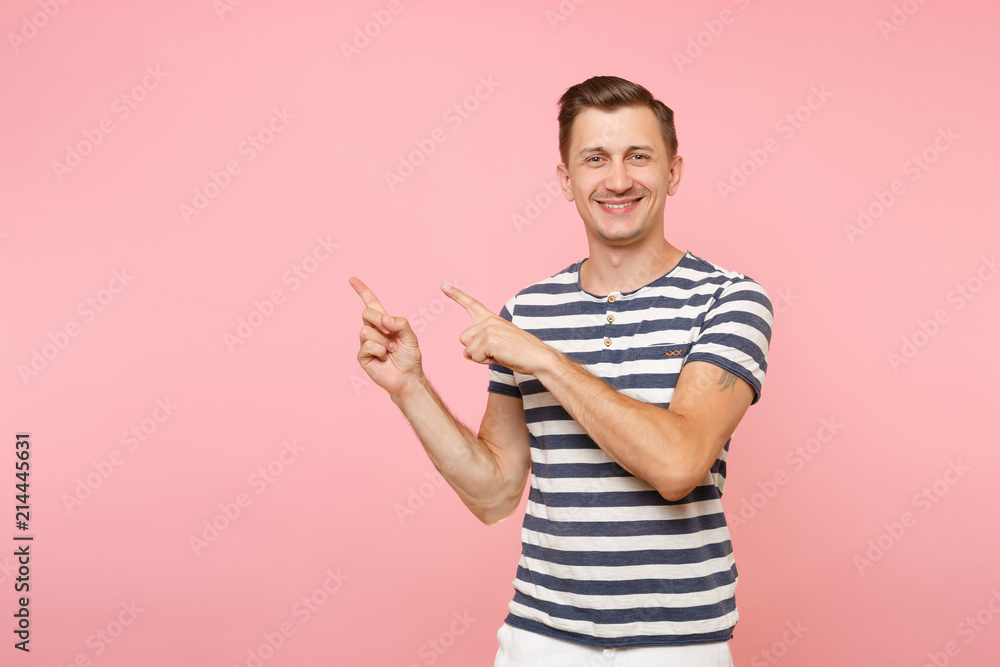 Portrait excited smiling young man wearing striped t-shirt pointing index fingers aside on copy space isolated on trending pink background. People sincere emotions lifestyle concept. Advertising area. Portrait excited smiling young man wearing striped t-shirt pointing index fingers aside on copy space isolated on trending pink background. People sincere emotions lifestyle concept. Advertising area.