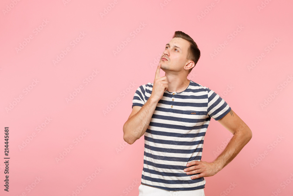 Portrait of handsome pensive young man in striped t-shirt thinking, put hand on chin face copy space isolated on trending pink background. People sincere emotions lifestyle concept. Advertising area. Portrait of handsome pensive young man in striped t-shirt thinking, put hand on chin face copy space isolated on trending pink background. People sincere emotions lifestyle concept. Advertising area.