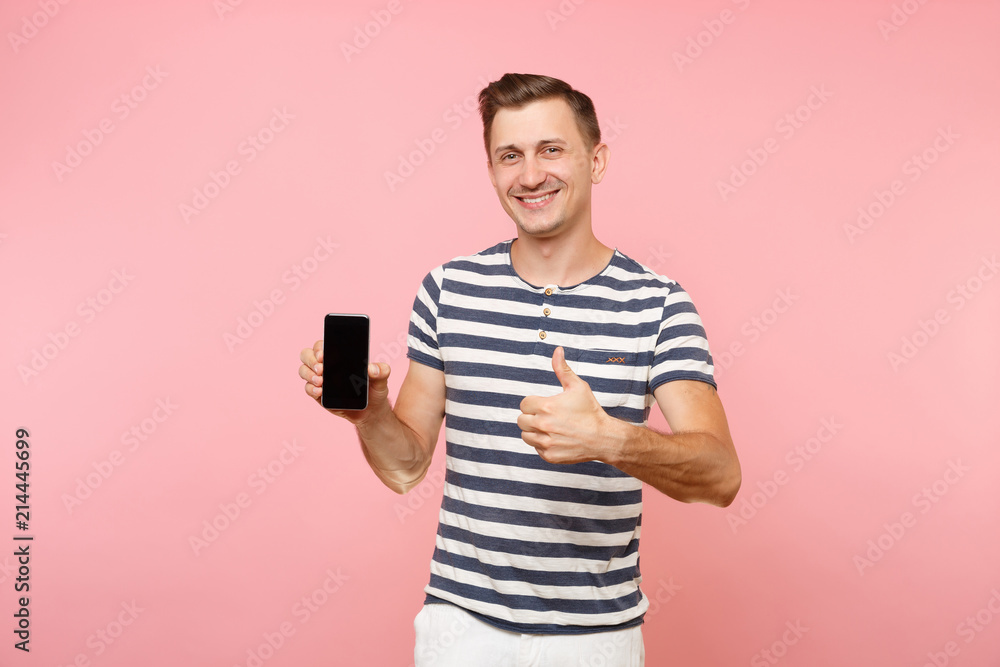Portrait of man in striped t-shirt showing mobile phone camera with blank black empty screen copy space isolated on trending pastel pink background. People sincere emotions concept. Advertising area. Portrait of man in striped t-shirt showing mobile phone camera with blank black empty screen copy space isolated on trending pastel pink background. People sincere emotions concept. Advertising area.