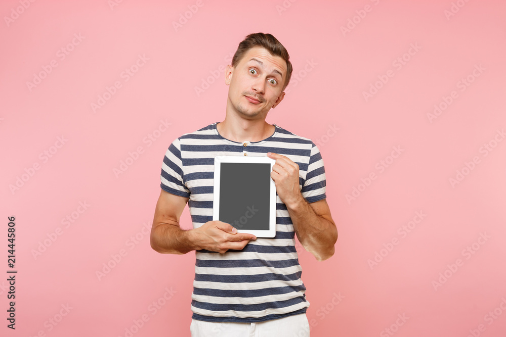 Portrait of young man holding tablet computer with blank black empty screen display touchscreen copy space isolated on trending pastel pink background. Technology lifestyle concept. Advertising area. Portrait of young man holding tablet computer with blank black empty screen display touchscreen copy space isolated on trending pastel pink background. Technology lifestyle concept. Advertising area.