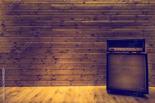 Guitar amplifier on wooden wall and floor, music studio photo