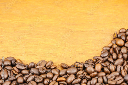 Coffee beans on brown wood background with copy space. © ningkub