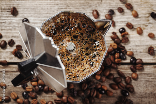 Moka coffee pot and coffee beans on wooden background
