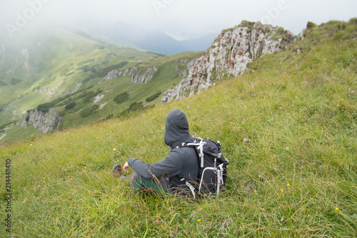 hiker sitting on grass in mountains © santiago silver