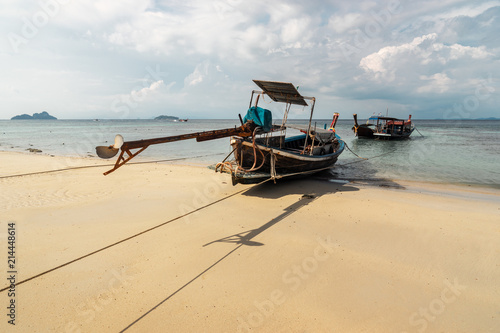 koh phi phi island - beach with longtail boats in front of ocean in thailand with sun shining