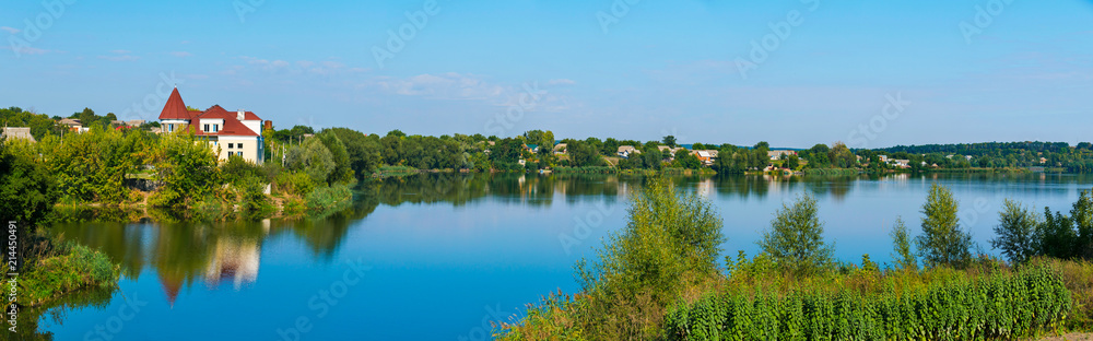 a small settlement under a blue sky on the shores of a wide deep lake a small settlement under a blue sky on the shores of a wide deep lake