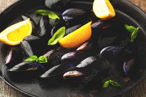 Raw mussels with lemon and herbs on a plate photo