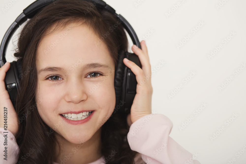 Cute little girl enjoying music using headphones Cute little girl enjoying music using headphones