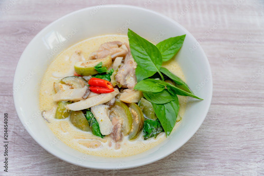 the white bowl of Green Curry with chicken, Thai delicious food on wooden table background. the white bowl of Green Curry with chicken, Thai delicious food on wooden table background.