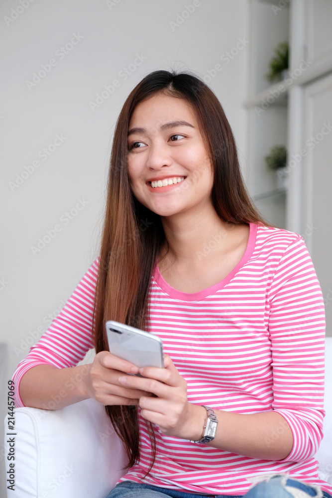 Young asian woman using smart phone with smiling, happy and relax emotion in white room background, people on phone, lifestyle Young asian woman using smart phone with smiling, happy and relax emotion in white room background, people on phone, lifestyle