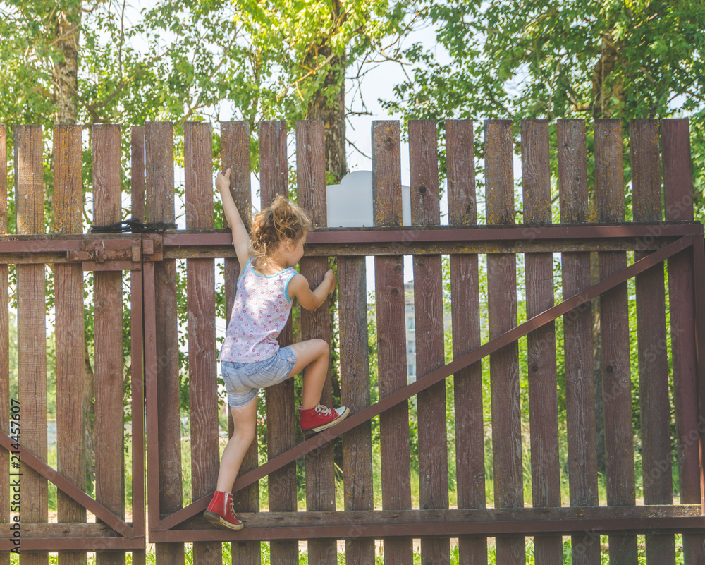 girl climbs the fence on a summer day girl climbs the fence on a summer day