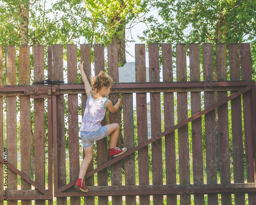 girl climbs the fence on a summer day