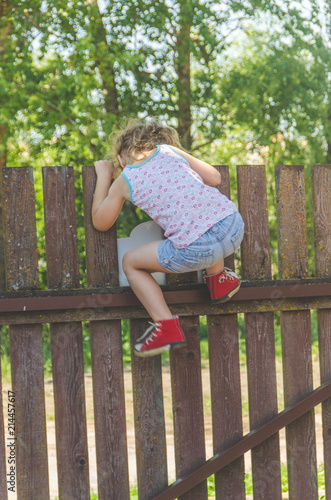 girl climbs the fence on a summer day