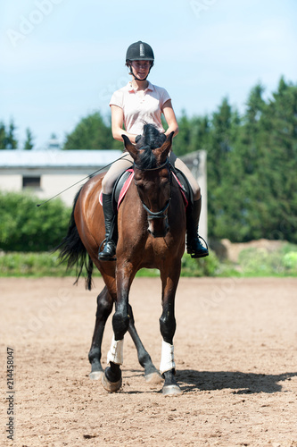 Teenage girl equestrian riding horseback on arena at sport training