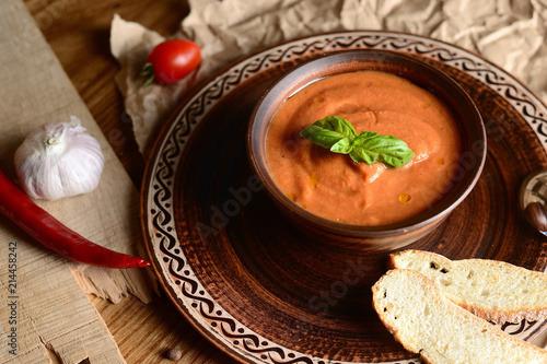 tomato cream soup with basil on a wooden table