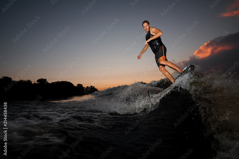 Man riding on the wakeboard on the pink sunset