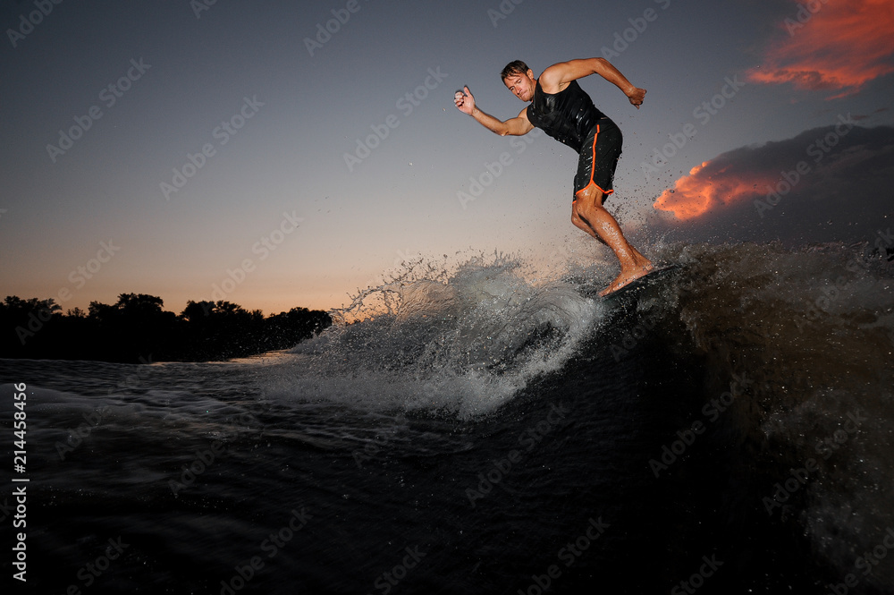 Young athletic man riding on the wakeboard on the pink sunset Young athletic man riding on the wakeboard on the pink sunset