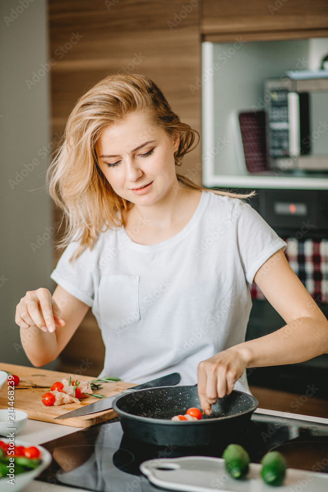 good-looking fair-haired housewife frying tomatoes on the cooker. prepare food according to the recipe good-looking fair-haired housewife frying tomatoes on the cooker. prepare food according to the recipe