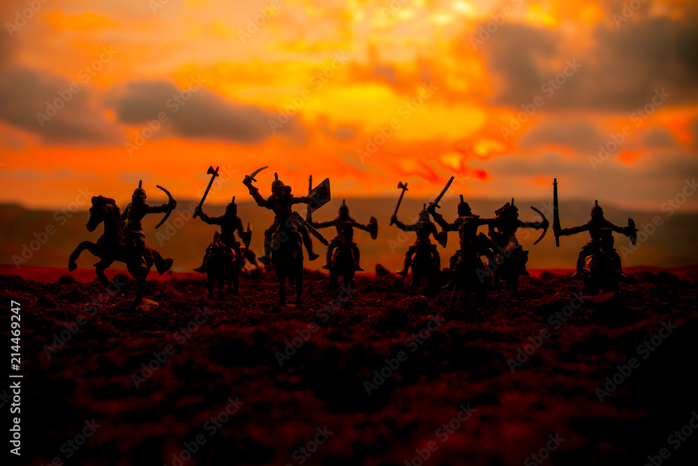 Medieval battle scene with cavalry and infantry. Silhouettes of figures as separate objects, fight between warriors on sunset foggy background. Medieval battle scene with cavalry and infantry. Silhouettes of figures as separate objects, fight between warriors on sunset foggy background.