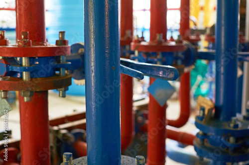 The blue valve on the hot water pipeline is painted red. Industrial background.