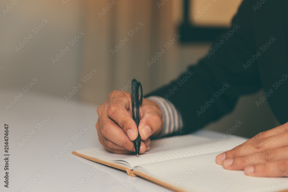 the hands of a businessman in a suit signing or writing a document the hands of a businessman in a suit signing or writing a document