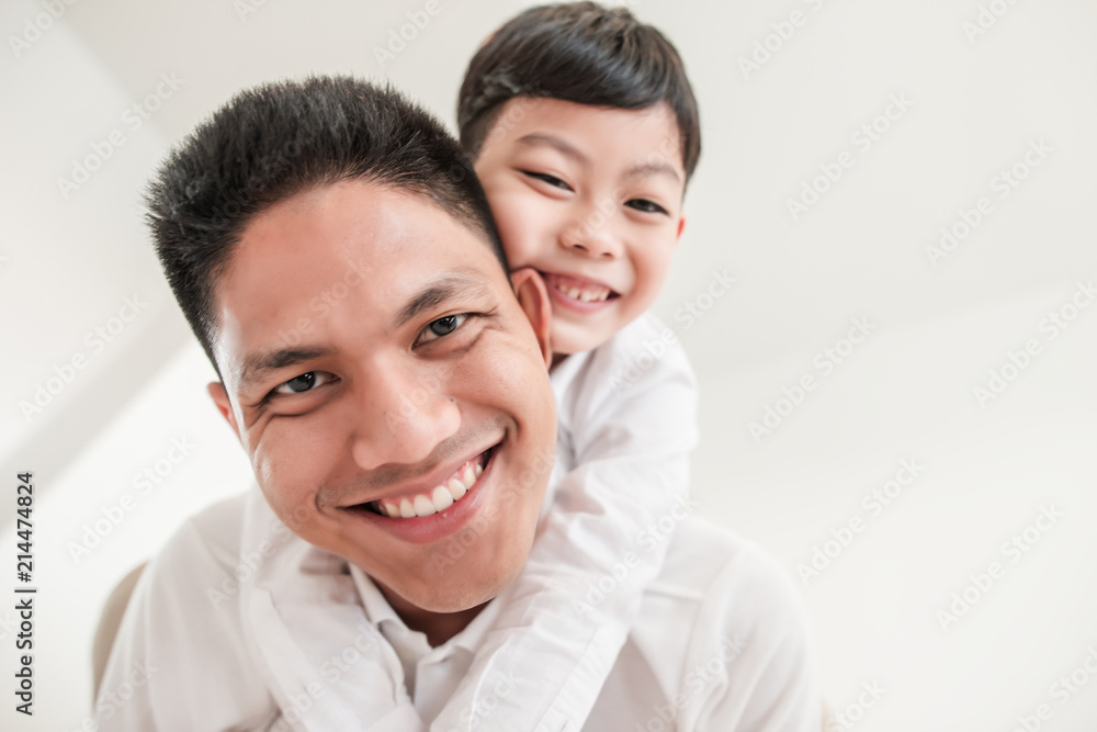 Happy father playing with son while lying on the bed at home Happy father playing with son while lying on the bed at home