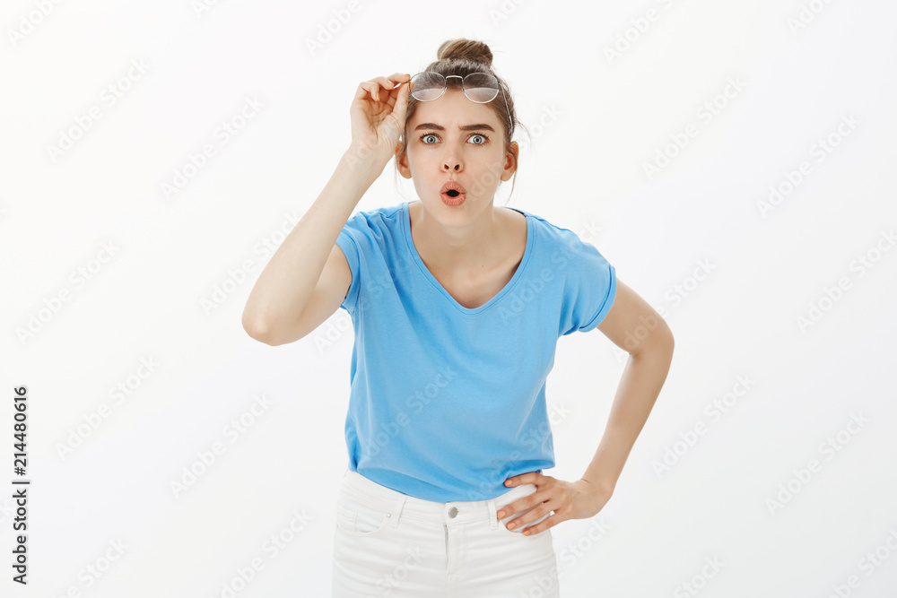 Let me look closer. Portrait of intrigued attractive female scientist, taking off glasses, bending towards camera with folded lips and hand on hip, being impressed and amused with curious thing Let me look closer. Portrait of intrigued attractive female scientist, taking off glasses, bending towards camera with folded lips and hand on hip, being impressed and amused with curious thing