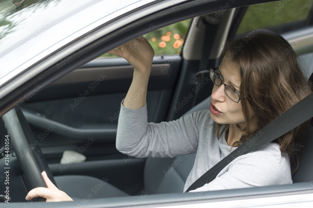 A female driver is indignant, screaming while sitting in the car. 