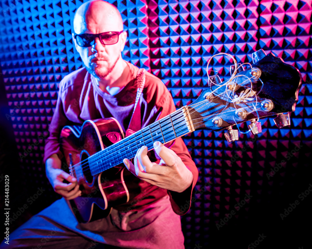 Obraz premium Young man playing on the acoustic guitar in sound recording studio.