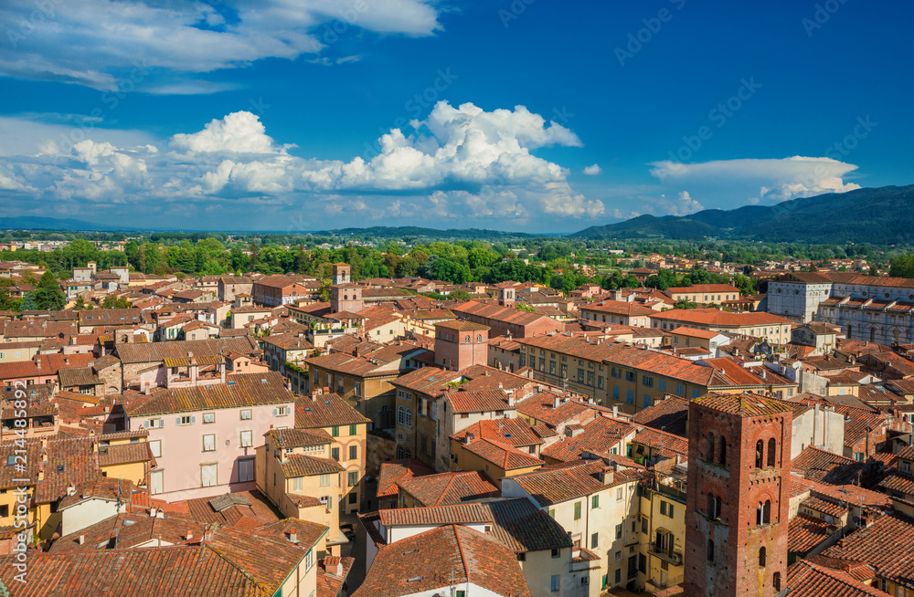 Panorama of the medieval center of Lucca with ancient towers, churches, roofs, mountains and clouds
