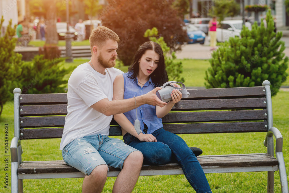 A young couple plays a game using virtual reality glasses on the street. A young couple plays a game using virtual reality glasses on the street.