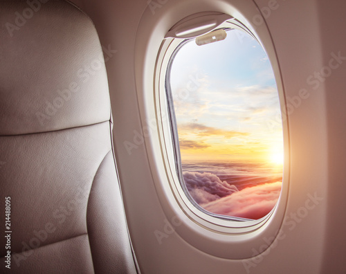 Airplane interior with window view of sunset above clouds. © Jag_cz