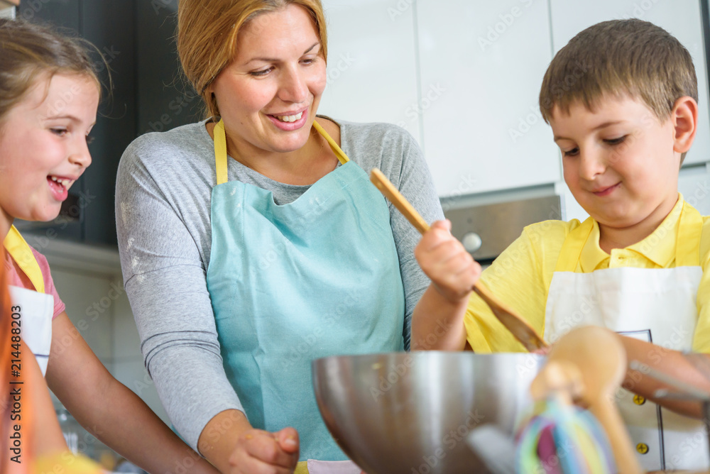 Mother and children together making apple pie in the kitchen at home. Children helping mother. Kitchen Activities for Children Mother and children together making apple pie in the kitchen at home. Children helping mother. Kitchen Activities for Children