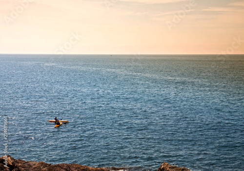 two people in kayak pause on the sea near the rocky coast