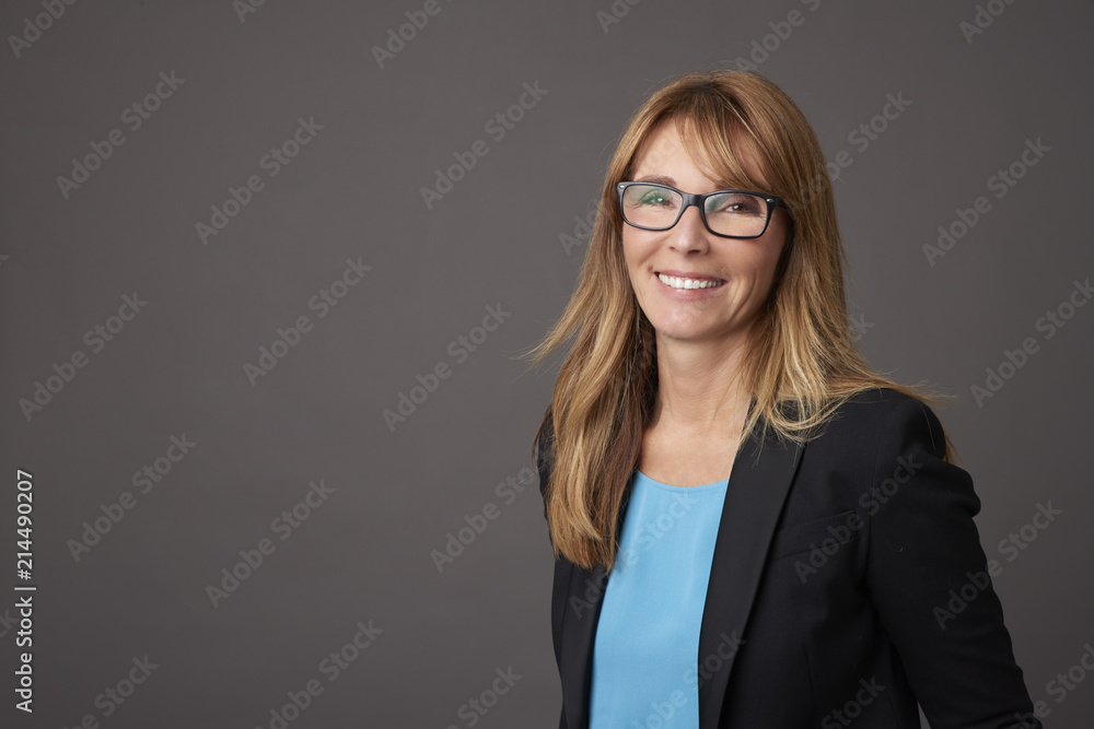 Confident female portrait. Portrait of an attractive middle aged woman posing against a grey background in the studio.