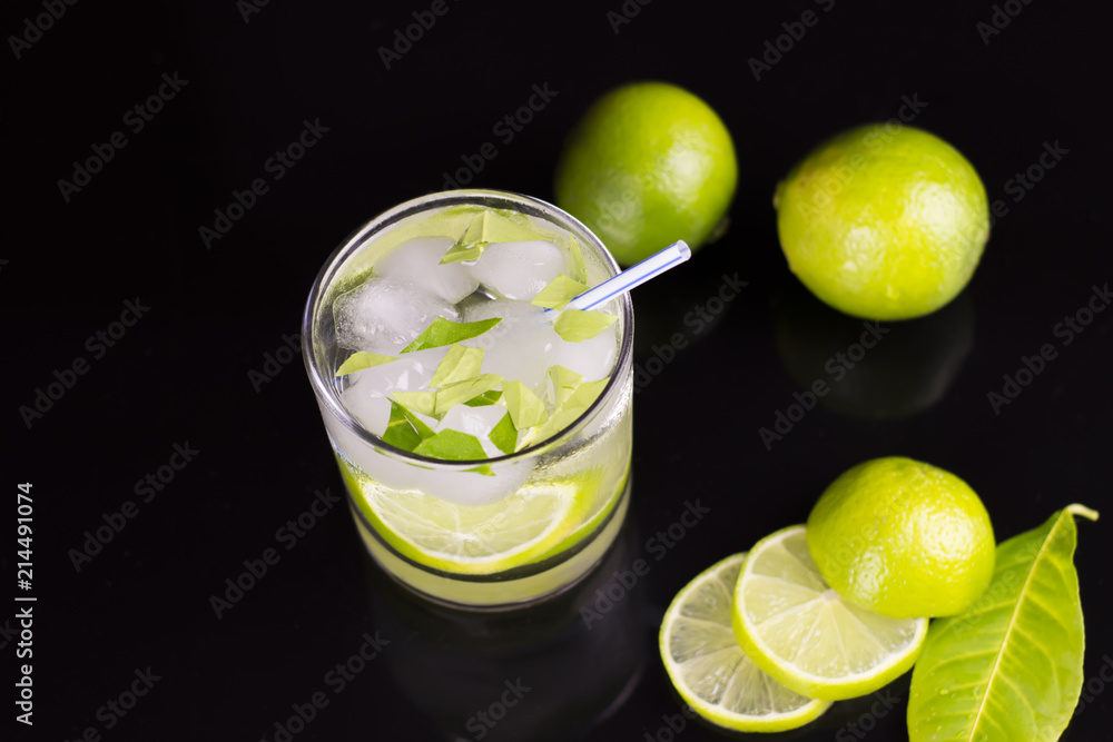 Alcohol drink (Gin Tonic cocktail) with lime and ice on black background with reflections Alcohol drink (Gin Tonic cocktail) with lime and ice on black background with reflections