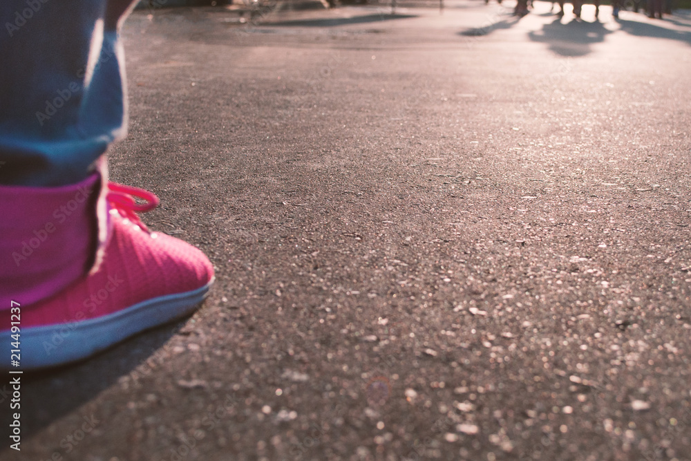 
legs in bright sneakers on the asphalt against the sunset background