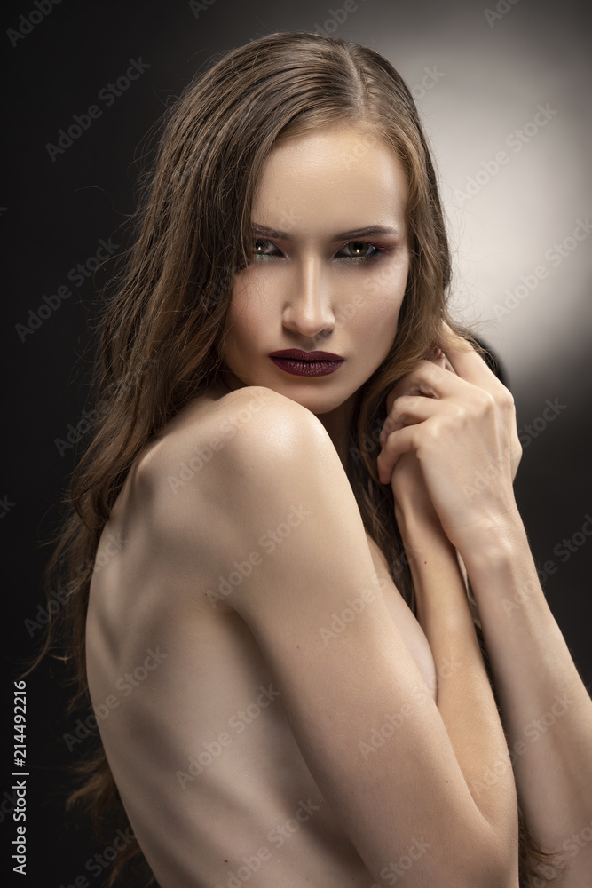 Beautiful slim flexible athletic topless girl model covers her naked breast with her hair on grey black gradient background. Healthy skin. Copy space. Beautiful slim flexible athletic topless girl model covers her naked breast with her hair on grey black gradient background. Healthy skin. Copy space.