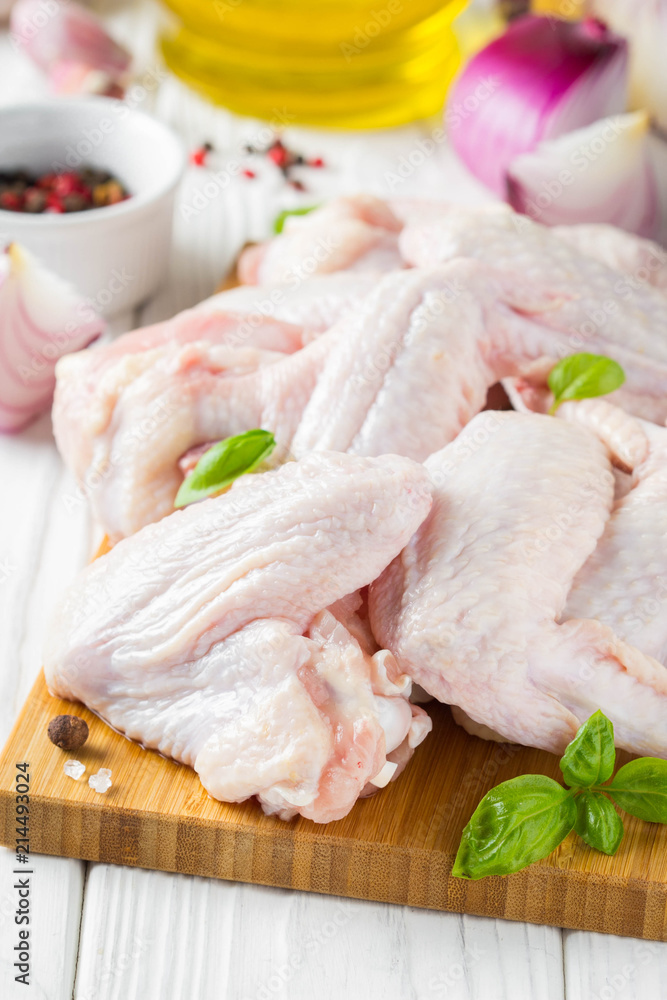 Raw chicken wings on a cutting board. Ingredients for cooking, spices, onion and garlic