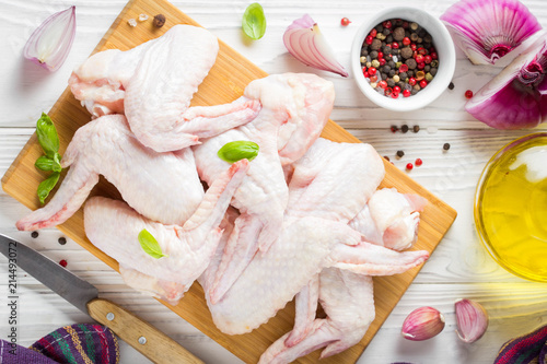 Raw chicken wings on a cutting board. Ingredients for cooking, spices, onion and garlic