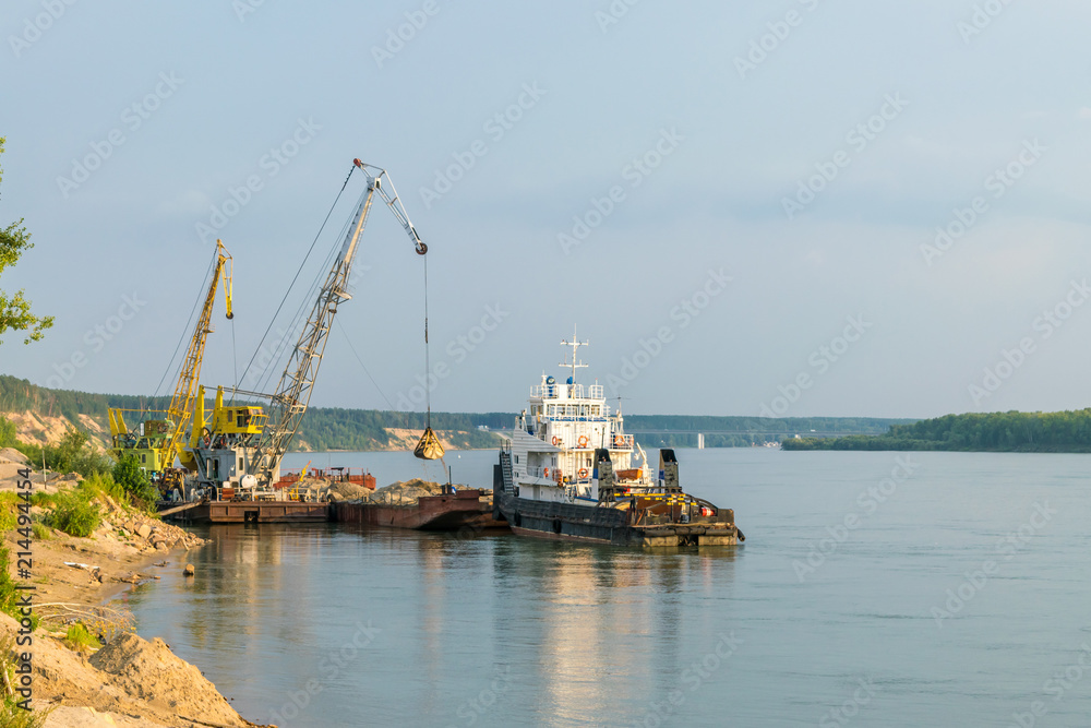 The crane unloads sand from the barge