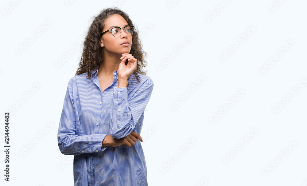 Beautiful young hispanic woman wearing glasses serious face thinking about question, very confused idea Beautiful young hispanic woman wearing glasses serious face thinking about question, very confused idea