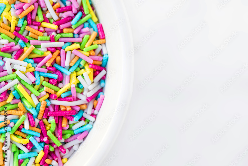 Fototapeta premium Sugar sprinkles in a bowl on a white background as decoration for cake and bakery. Top view