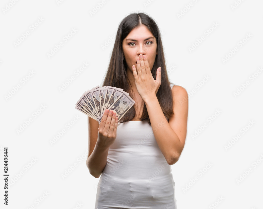 Young hispanic woman holding dollars cover mouth with hand shocked with shame for mistake, expression of fear, scared in silence, secret concept Young hispanic woman holding dollars cover mouth with hand shocked with shame for mistake, expression of fear, scared in silence, secret concept
