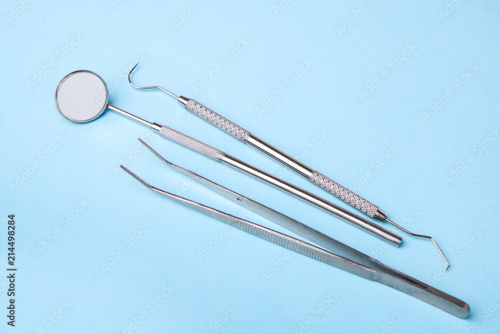 Dental instruments. Dental mirror, probe hook, tweezers on blue Dental instruments. Dental mirror, probe hook, tweezers on blue