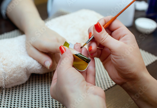 Nail technician makes nail extensions gel in the beauty salon. Professional care for hands. photo