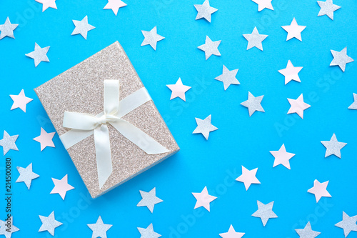 Flat lay of woman hands holding gift wrapped and decorated with bow on blue background with copy space