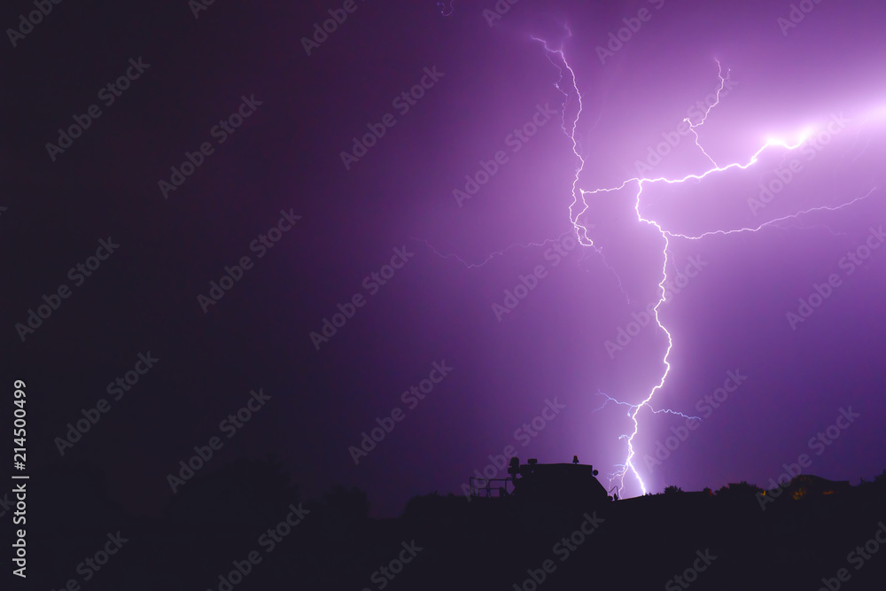 flash of lightning in the night sky color it in an incredibly beautiful violet color illuminating the trees